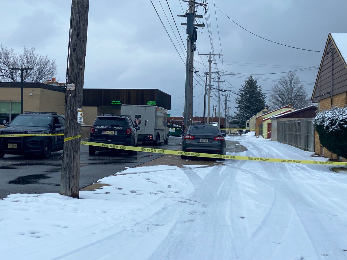 An armored truck is surrounded by police tape, just outside North Shore Bank on 80th & Capital in Milwaukee. There is a police presence, with officers knocking on doors nearby.